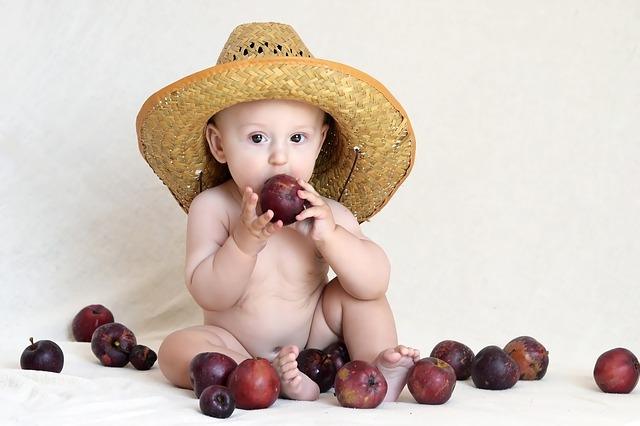 Foto av en baby i hatt og med plommer