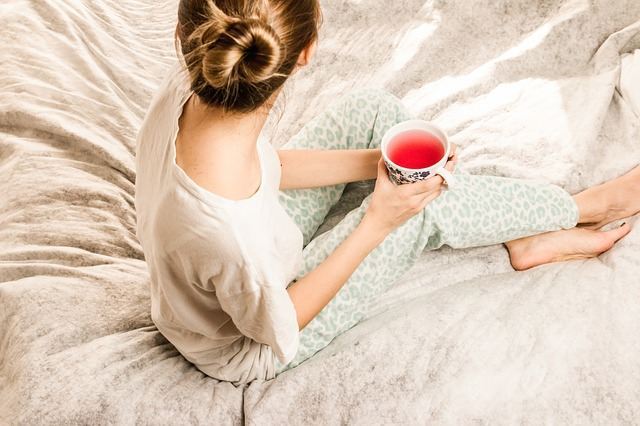 Femme avec du thé sur le lit